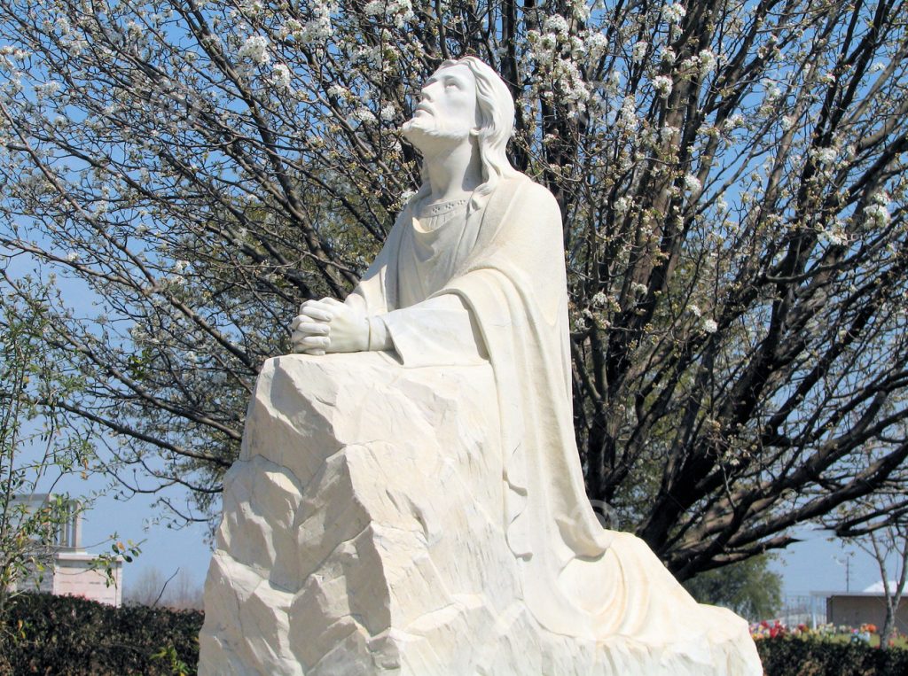 Jesus praying on a rock in a garden setting
